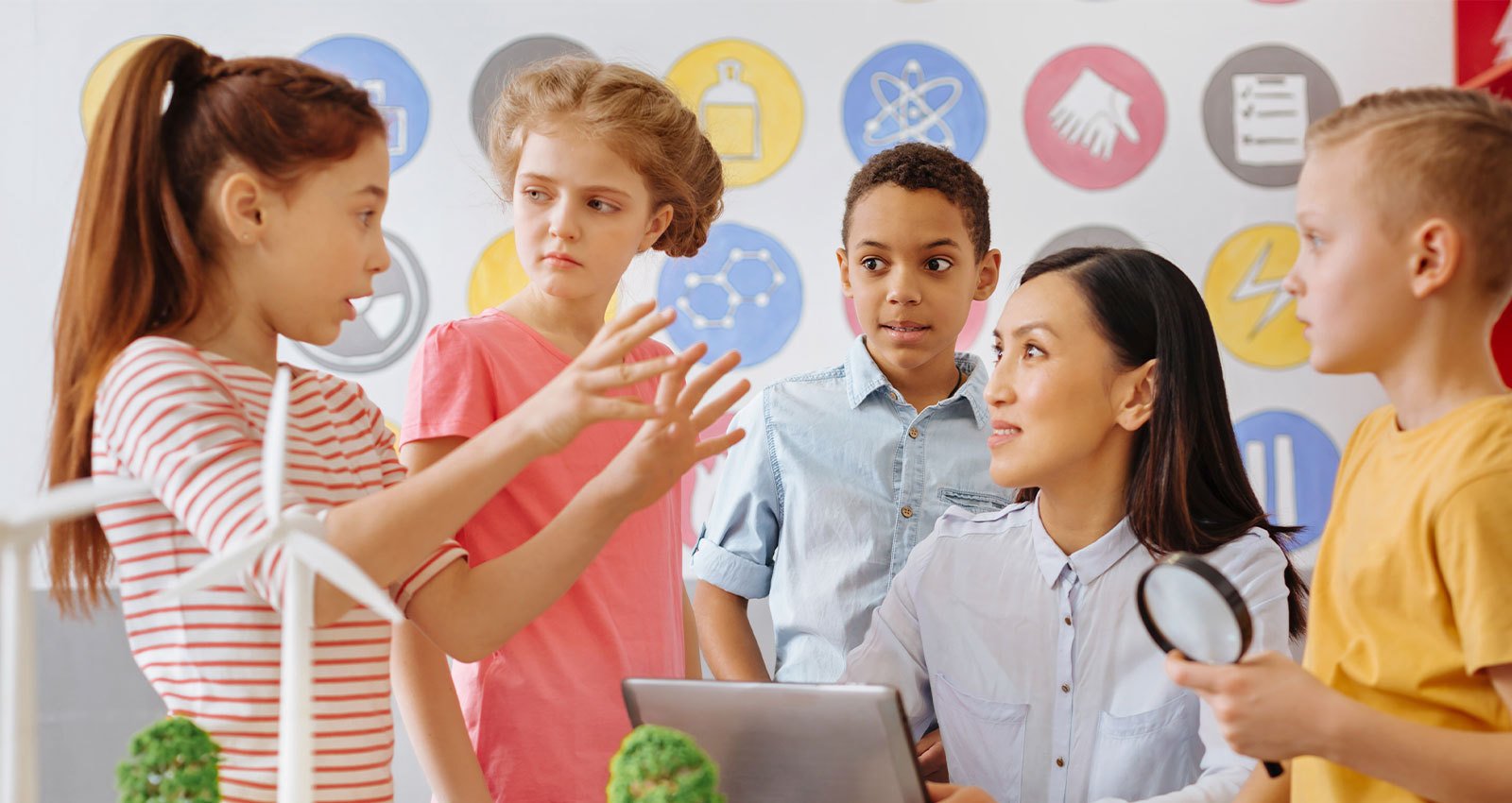 A student leads a group discussion, explaining an idea to her classmates and teacher.